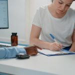 Nurse writing on a clipboard while talking to a sick girl in a hospital bed and her mother.